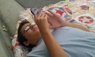 teenage boy laying on ground looking at his phone