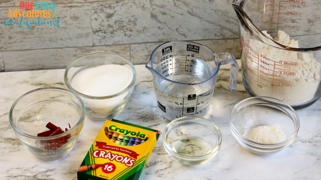 measuring cups, bowls all filled with items to make crayon play doh
a box of crayons